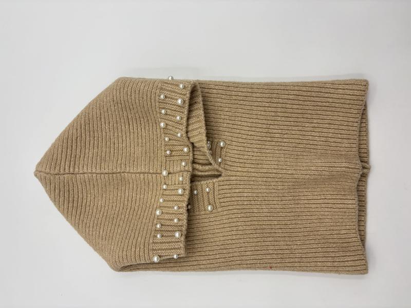 Folded beige ribbed knit infinity scarf with pearl bead trim detail, laid flat on white background