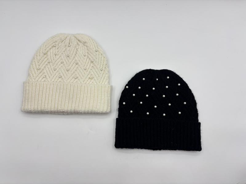 Two knit beanies with pearl embellishments side by side, cream chevron pattern and solid black, ribbed cuff winter hats