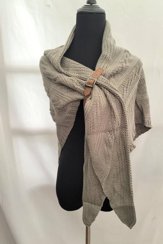 Beige chunky cable knit wrap shawl with brown leather buckle clasp displayed on a black dress form mannequin