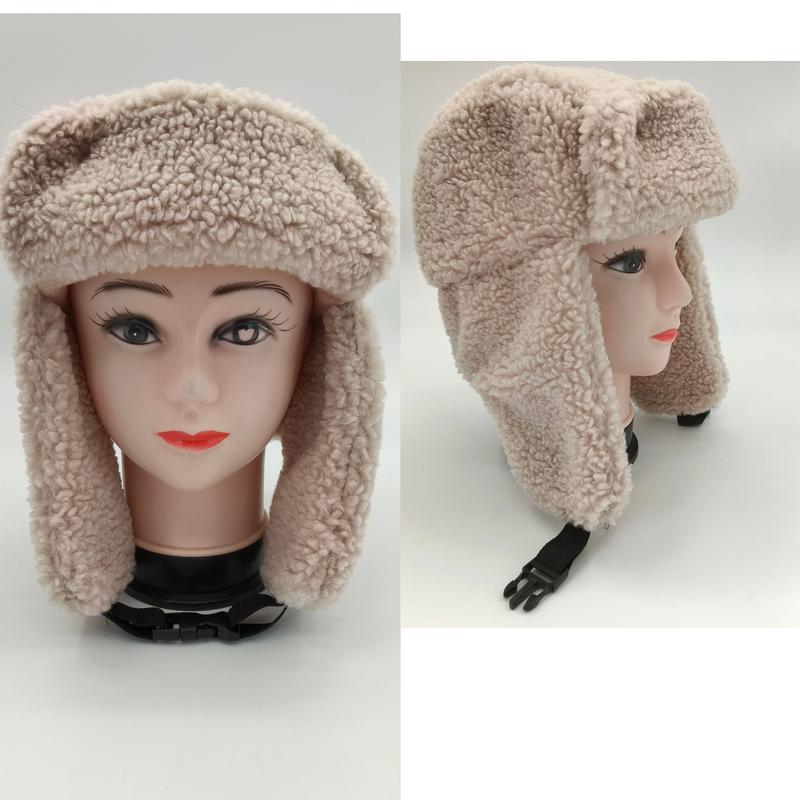 Cream sherpa fleece trapper ushanka hat with foldable ear flaps and adjustable chin strap shown on mannequin head, front and side view