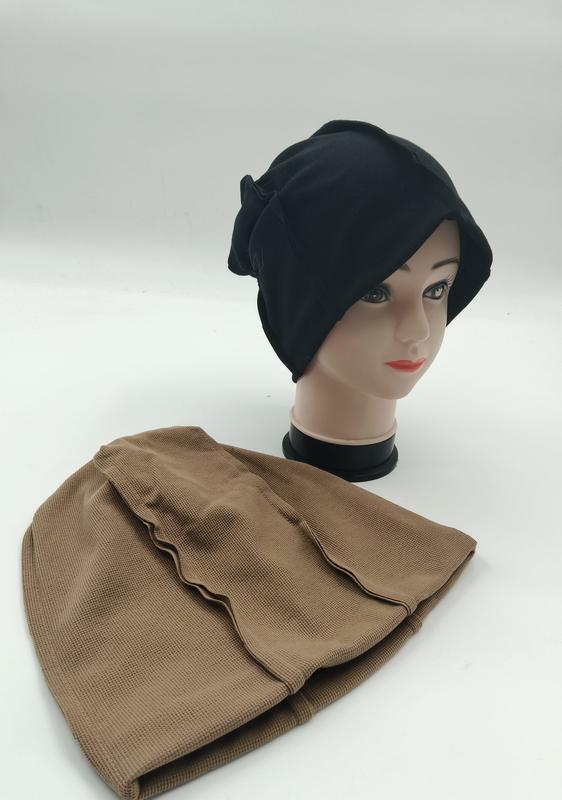 Black slouchy beanie hijab underscarf on mannequin head with tan textured inner cap laid flat beside it