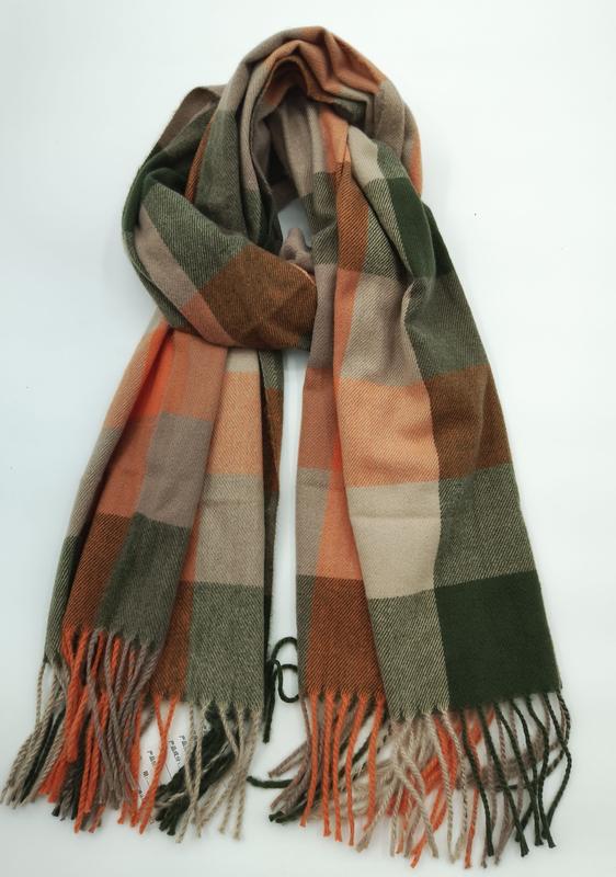 Folded plaid scarf in olive green, burnt orange, and beige large check pattern with twisted fringe ends on white background