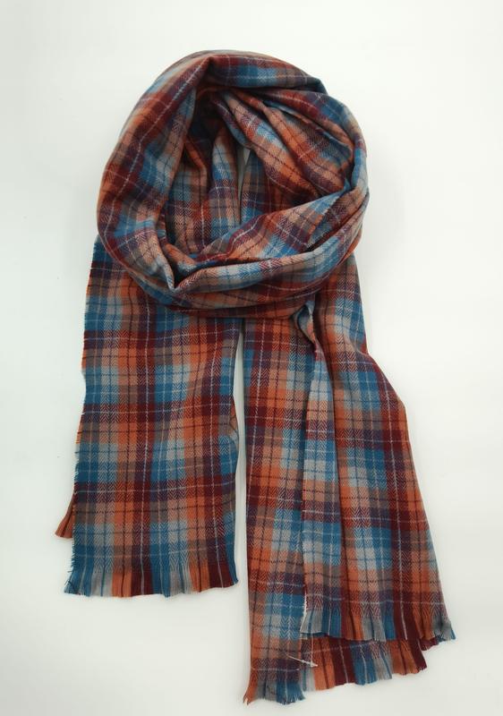 Folded plaid scarf in rust orange, teal blue, and burgundy with fringe edges displayed on white background
