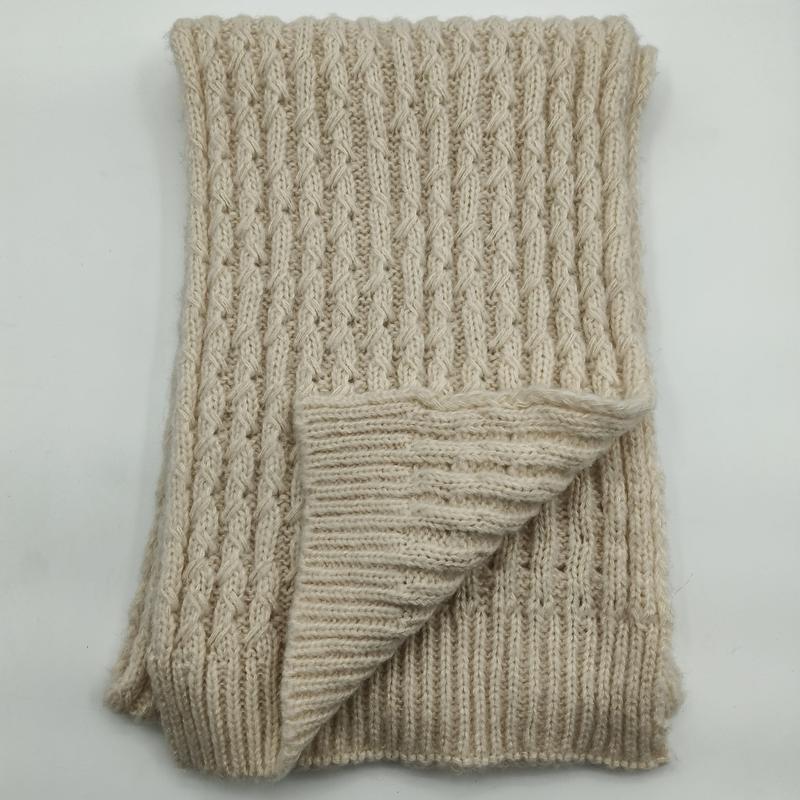 Folded cream chunky cable knit throw blanket showing ribbed texture and reverse side on white background