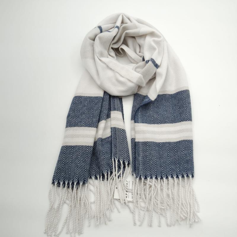 Navy blue and cream herringbone woven scarf with bold stripes and tassel fringe ends, coiled on white background