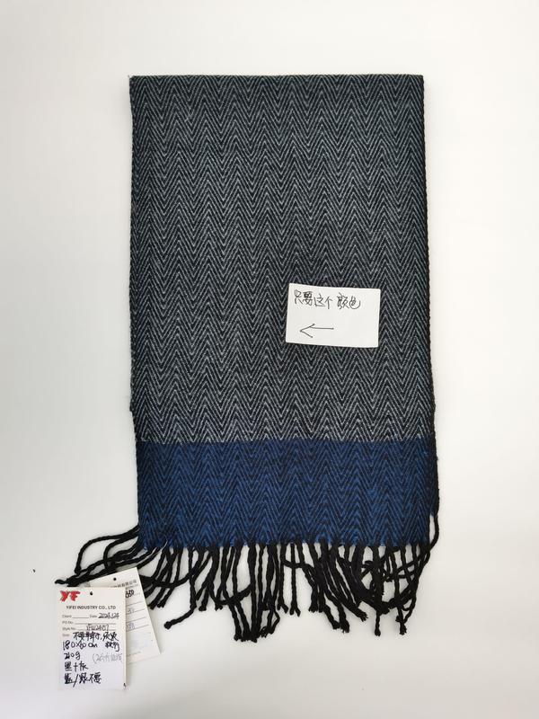 Grey and blue herringbone woven scarf with color block design and black fringe trim, laid flat on white background