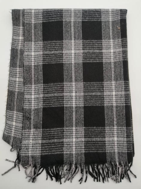 Folded black and white tartan plaid woven throw blanket with knotted fringe trim on white background