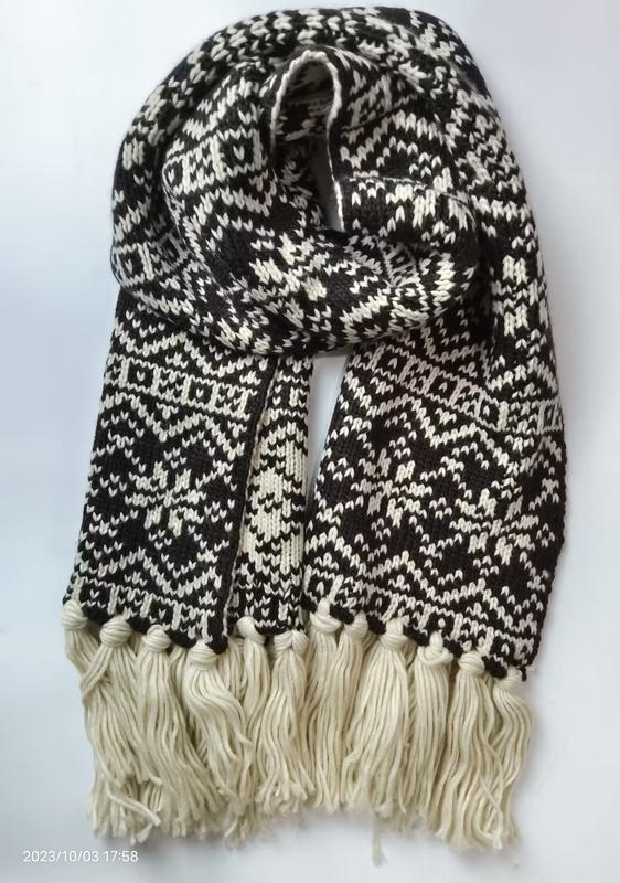 Black and cream Fair Isle patterned knit scarf with chunky tassel fringe ends, folded to display geometric snowflake design