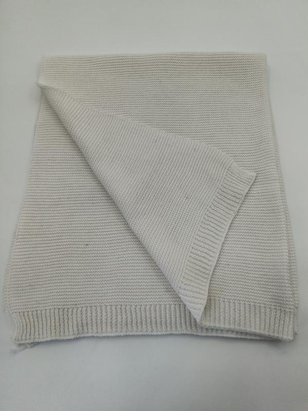 Folded cream chunky knit cotton throw blanket with ribbed edges, showing textured weave pattern on white background