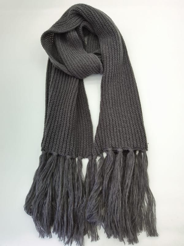 Charcoal gray chunky ribbed knit scarf with long tassel fringe ends, loosely draped on white background