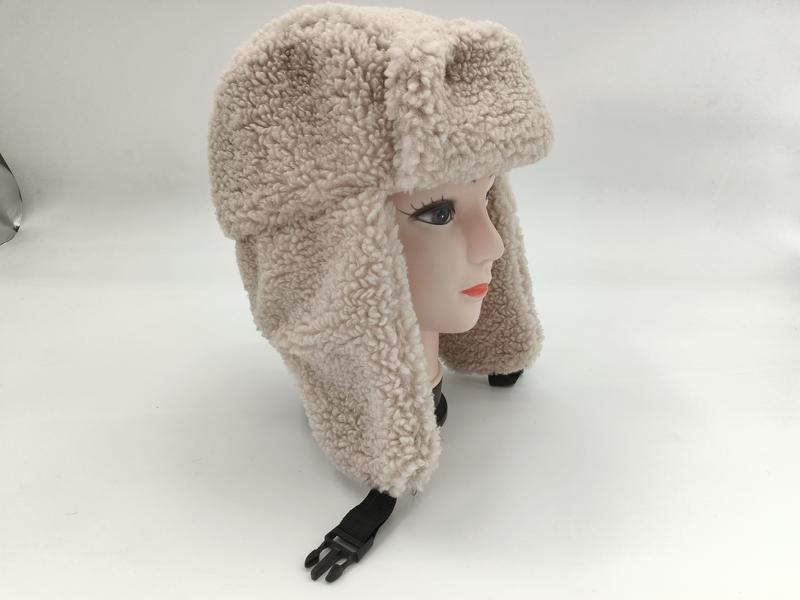 Cream curly sherpa fleece trapper ushanka hat with ear flaps and black plastic buckle chin strap on mannequin head