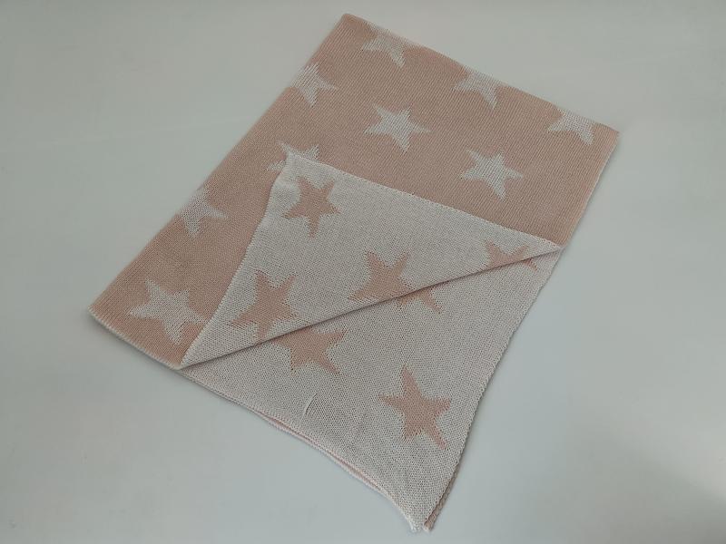 Folded blush pink and white cross pattern knit throw blanket showing reversible two-tone design on light background