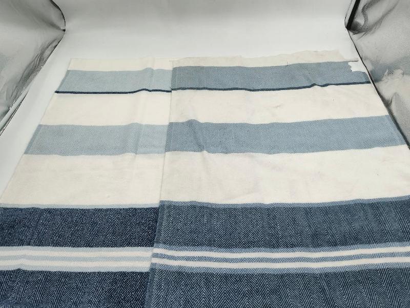 Flat lay of a herringbone weave cotton throw blanket with navy blue, light blue, and white horizontal stripes