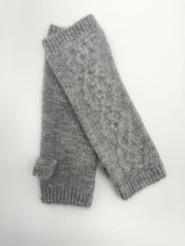 Pair of gray cable knit fingerless gloves with ribbed cuffs and thumb holes laid flat on white background