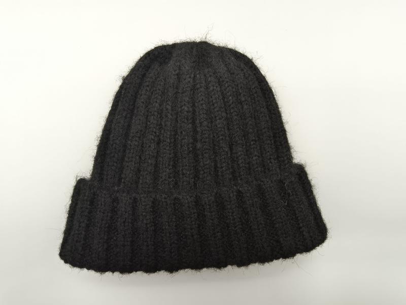 Black chunky ribbed knit beanie hat with folded cuff, laid flat on white background, fuzzy wool texture