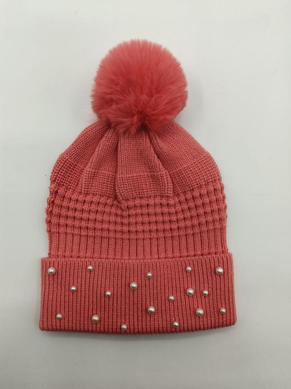 Coral pink ribbed knit winter beanie hat with faux fur pom pom and pearl stud embellishments on cuff