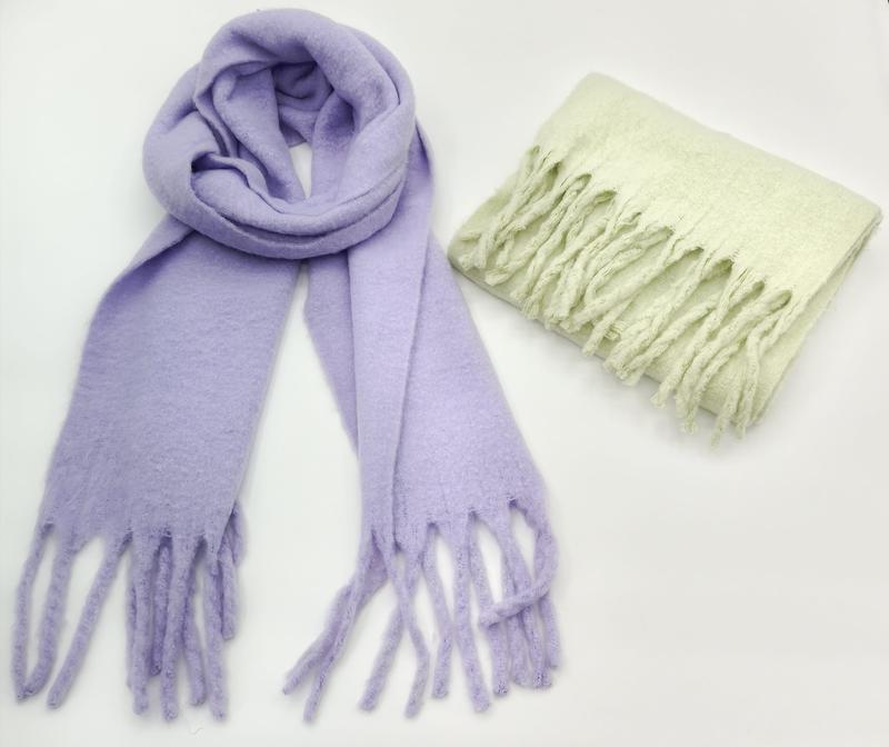 Two soft fuzzy scarves with fringe ends: one lavender looped open and one mint green folded, on white background