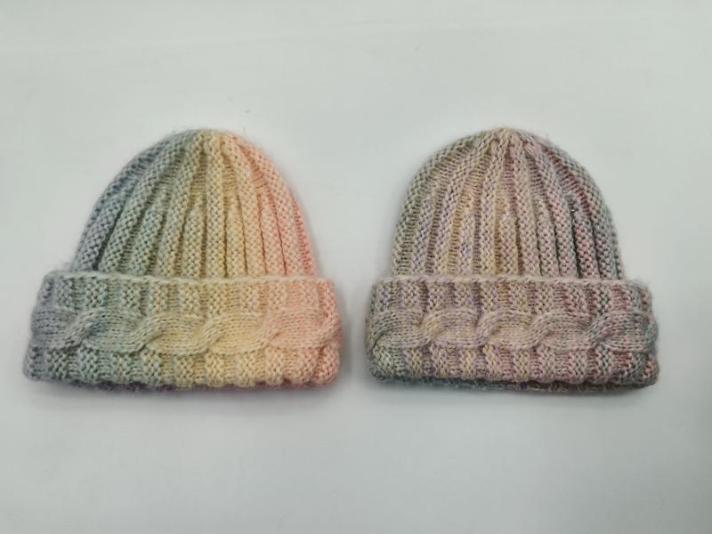 Two hand-knitted pastel variegated beanies with cable cuff detail, one in green-yellow-peach and one in muted pink-taupe tones