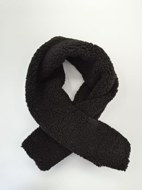Black sherpa fleece scarf looped and crossed on white background showing thick curly teddy texture