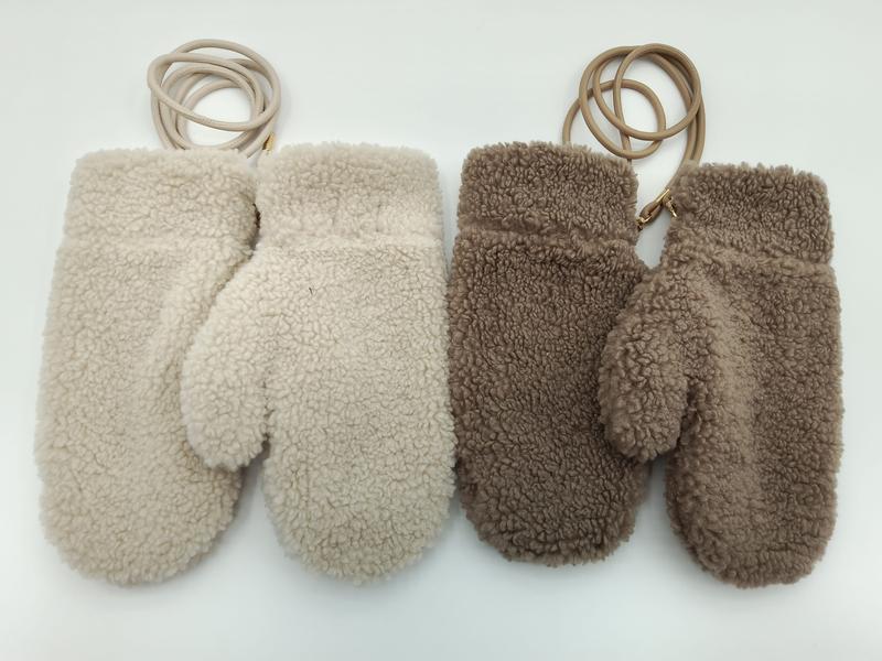 Two pairs of fluffy sherpa fleece mittens in cream and taupe brown, each connected by a leather wrist cord, laid flat on white background