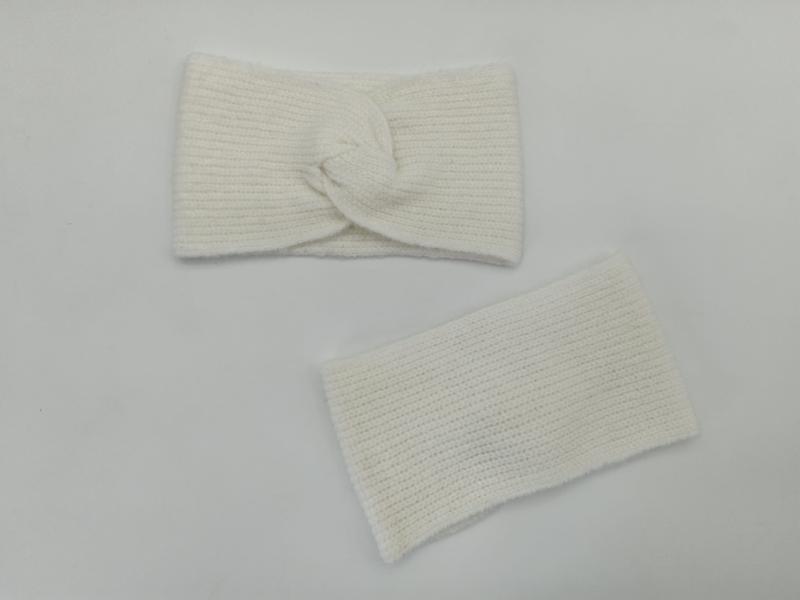 Cream ribbed knit twisted turban headband and matching wrist warmer set laid flat on white surface