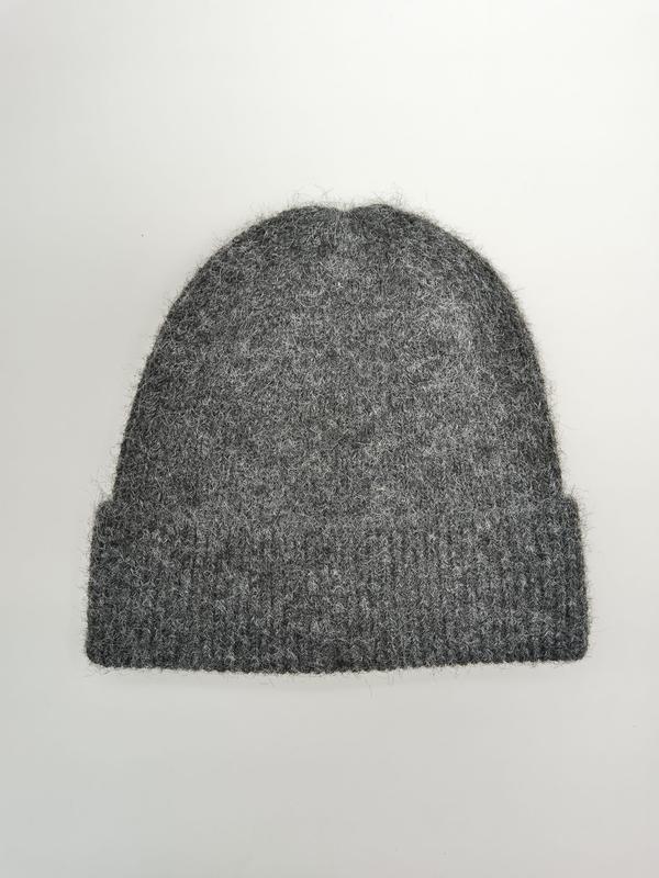 Grey fluffy knit beanie hat with ribbed cuff, laid flat on white background, soft wool blend winter hat