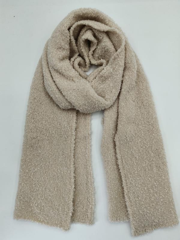 Oversized beige boucle knit scarf loosely wrapped and laid flat on white background
