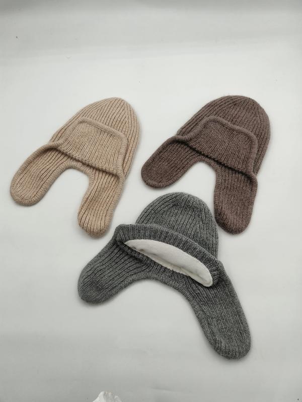 Three ribbed knit earflap beanies in beige, brown, and gray laid flat on white background