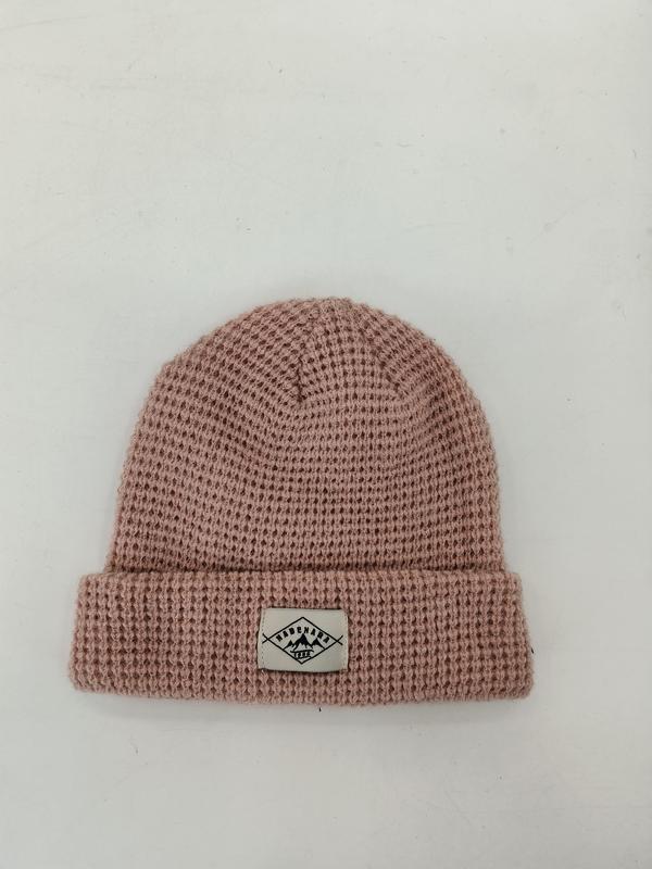 Dusty pink waffle knit cuffed beanie hat with woven label patch on white background