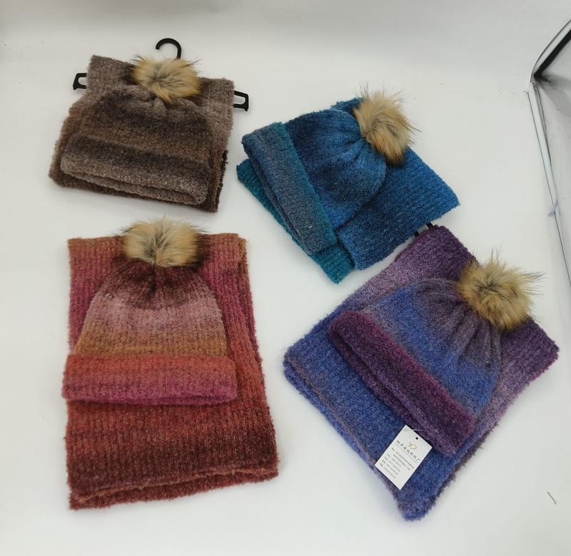 Four knit hat and scarf sets in brown, blue, red-orange gradient, and purple gradient, each with a faux fur pompom