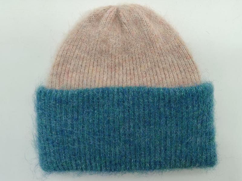 Soft fuzzy knit beanie hat with blush pink crown and wide teal ribbed cuff, flat lay on white background