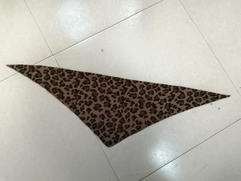 Triangular leopard print fabric bandana scarf with brown and black cheetah spots laid flat on white tile floor