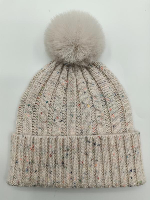 Cream cable knit winter beanie hat with multicolor fleck detailing and large fluffy faux fur pom pom on top