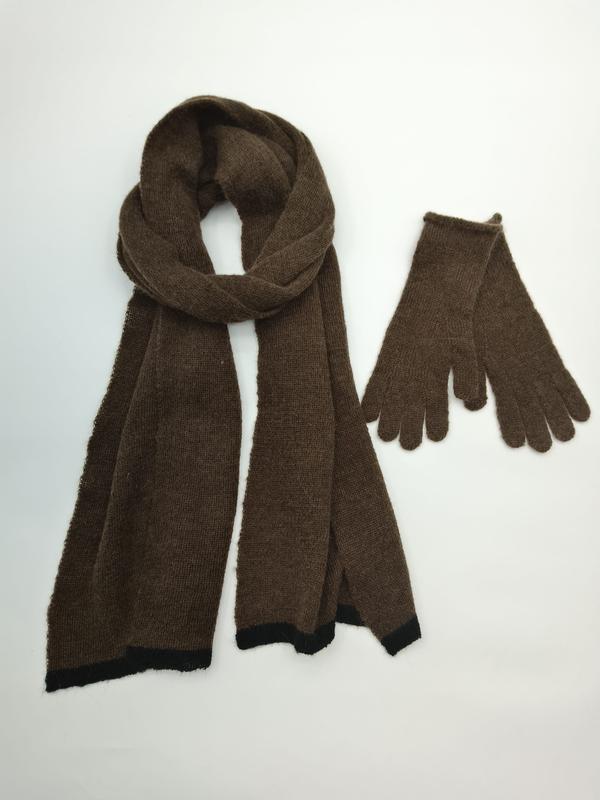 Brown knitted scarf looped and matching gloves set with black trim detail on white background