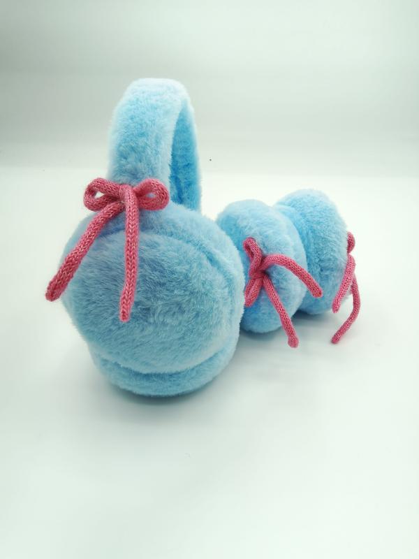 Baby blue plush earmuffs with pink knitted bow decorations laid flat on white background
