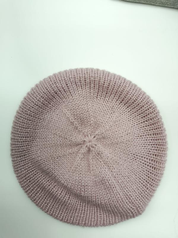 Top view of a dusty rose pink ribbed knit beret hat laid flat on a white surface, showing spiral crown detail
