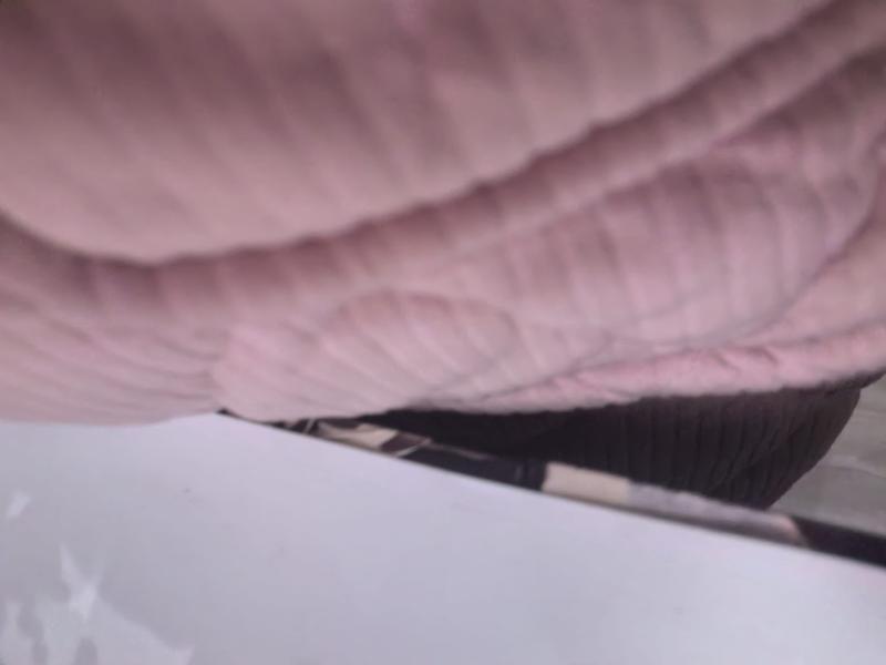 Close-up of a soft blush pink quilted throw blanket with raised waffle weave texture draped over a surface