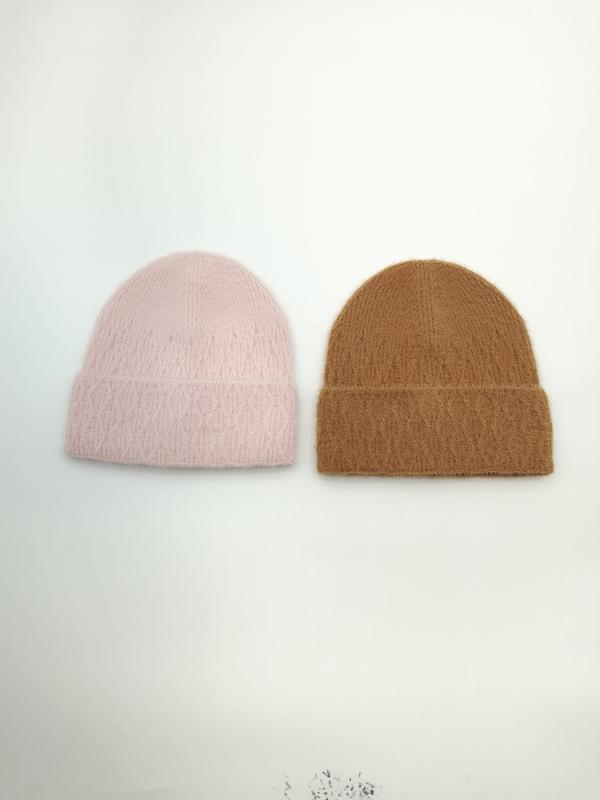 Two fluffy knit beanies laid flat on white surface, one in blush pink and one in camel brown, both with folded cuffs